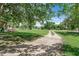 Expansive green front yard and gravel driveway leading to the property with shade trees at 12526 Spottswood Dr, Riverview, FL 33579