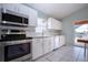 Modern kitchen with stainless steel appliances, white cabinets, and backyard pool view at 2211 N Creek Ct, Sun City Center, FL 33573