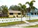 Inviting yellow home with pineapple-themed picket fence, palm trees, and sidewalk leading to the front door at 2526 44Th S St, St Petersburg, FL 33711