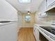 Galley kitchen with wood floors, white appliances, and a window into the dining area at 11485 Oakhurst Rd # A301, Largo, FL 33774