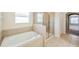 Bright bathroom showcasing a soaking tub, separate glass shower, and neutral tile flooring at 20209 Merry Oak Ave, Tampa, FL 33647