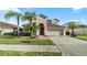 Charming two-story home with manicured lawn, mature palms, arched entry, and attached two-car garage at 4110 Huntingdale Ct, Wesley Chapel, FL 33543