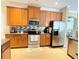 Kitchen featuring stainless steel appliances, tiled floors, and warm wood cabinetry at 4110 Huntingdale Ct, Wesley Chapel, FL 33543