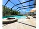 Screened-in pool with a fire pit, sun shelf, and travertine tile deck is perfect for outdoor entertaining at 4110 Huntingdale Ct, Wesley Chapel, FL 33543