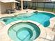 Backyard oasis featuring a spa, sun shelf, and a swim-up table with a screened-in enclosure at 4110 Huntingdale Ct, Wesley Chapel, FL 33543