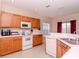 Functional kitchen with wooden cabinets, white appliances, ample counter space and a tiled floor at 25925 Terrawood Loop, Land O Lakes, FL 34639