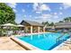 Community pool featuring a tanning ledge, lounge chairs, and tables with umbrellas at 3151 Landmark Dr # 123, Clearwater, FL 33761