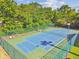 Aerial view of fenced blue and green tennis courts surrounded by tall green trees at 3151 Landmark Dr # 123, Clearwater, FL 33761