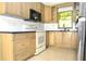 A modern kitchen with stainless steel appliances, light wood cabinets, and tile backsplash at 5565 Salem Square N Dr, Palm Harbor, FL 34685