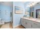 Bright blue bathroom features white cabinetry, quartz countertops, and elegant beach-themed artwork at 10532 94Th Pl, Seminole, FL 33772