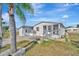 Charming home exterior showcasing a screened porch, palm trees, and a well-maintained yard, perfect for outdoor enjoyment at 206 S Port Royal Ln, Apollo Beach, FL 33572