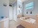 Bright bathroom featuring a soaking tub, large window, tile flooring and a neutral color palette at 6467 Willowshire Way, Bradenton, FL 34212