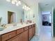 Bathroom features a double vanity with wood cabinets and a large mirror, with views of the shower and bedroom at 6467 Willowshire Way, Bradenton, FL 34212