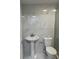 Stylish bathroom with a pedestal sink, white toilet, and marble tile at 8807 Oak Cir, Tampa, FL 33615