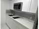 Modern kitchen with white cabinets, stainless steel microwave, and sleek backsplash at 8807 Oak Cir, Tampa, FL 33615