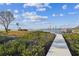 Inviting dock leads to calm water and a grassy shore, under a beautiful, partly cloudy blue sky at 1640 Sea Breeze Dr, Tarpon Springs, FL 34689