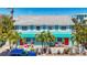 Bright turquoise coastal duplex with red doors, white picket fence, and lush palm trees in a sunny setting at 308 2Nd St N # 202, Bradenton Beach, FL 34217