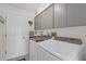 Well-lit laundry room featuring front loading washer, dryer, and overhead cabinets at 9229 Water Hazard Dr, Hudson, FL 34667
