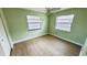 Bedroom featuring wood-look floors, fan, and bright natural light from two windows at 1670 Monterey Dr, Clearwater, FL 33756
