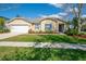 Charming single-story home featuring a two-car garage, blue shutters and a manicured lawn with landscaping at 5249 Moon Shell Dr, Apollo Beach, FL 33572