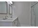 Bathroom with double sinks, a white vanity, framed mirrors, and a glass shower door at 5729 13Th St, Zephyrhills, FL 33542