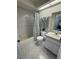 Clean bathroom with shower-tub, toilet, and sink, featuring white tile flooring and a decorative shower curtain at 9337 Zamora Dr, New Port Richey, FL 34655
