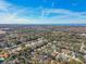 Expansive aerial view of a residential neighborhood with tree-lined streets and distant water views under a vibrant blue sky at 1764 Oak Spring Dr, Tarpon Springs, FL 34689