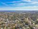 A high angle shows homes in a leafy neighborhood near a lake under a bright blue sky with scattered clouds at 1764 Oak Spring Dr, Tarpon Springs, FL 34689
