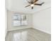 Bright bedroom with a large window, ceiling fan, and wood-look tile flooring, creating a serene atmosphere at 1764 Oak Spring Dr, Tarpon Springs, FL 34689