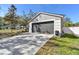 Attached two-car garage with a gray door and ample driveway space, complemented by verdant landscaping at 1764 Oak Spring Dr, Tarpon Springs, FL 34689