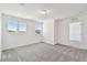 Bright bedroom featuring three windows, neutral walls, gray carpet, and a standard ceiling light fixture at 36424 Sespe Creek Ct, Zephyrhills, FL 33540