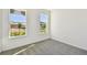 Minimalist bedroom with gray carpeting and two windows offering neighborhood views at 36424 Sespe Creek Ct, Zephyrhills, FL 33540