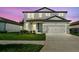 Charming home boasts modern gray exterior, two-car garage, and well-manicured lawn against a captivating twilight sky at 36424 Sespe Creek Ct, Zephyrhills, FL 33540