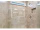 Walk-in shower with tiled walls, glass door, overhead shower head and built-in shelf at 36424 Sespe Creek Ct, Zephyrhills, FL 33540
