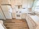 Cozy kitchen featuring white appliances, laminate counters, wood cabinets, and updated wood-look flooring at 6075 Shore S Blvd # 605, Gulfport, FL 33707