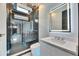 Modern bathroom showcasing black marble walls, a glass shower and a sleek white vanity with a lighted mirror at 6538 Simone Shores Cir, Apollo Beach, FL 33572