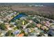 Aerial view of a home nestled among trees, showcasing a pool, surrounding neighborhood, and nearby lake at 5292 Kernwood Ct, Palm Harbor, FL 34685