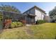 Backyard view showcasing screened-in pool, lush landscaping, and the exterior of the home at 5292 Kernwood Ct, Palm Harbor, FL 34685