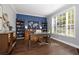 Well-lit office space with a dark blue accent wall, built-in bookshelves, and a large window at 5292 Kernwood Ct, Palm Harbor, FL 34685