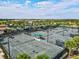 Aerial view of tennis courts with players, and the surrounding community and lush landscaping at 5749 Cheech Gln, Bradenton, FL 34211