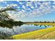 Scenic view of a lake reflecting clouds, with a grassy lawn and palm trees at 5749 Cheech Gln, Bradenton, FL 34211