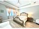 Bedroom featuring a tray ceiling, decorative bed frame, wood tile flooring, and matching bedside tables with lamps at 5749 Cheech Gln, Bradenton, FL 34211