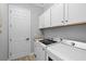 Laundry room with modern appliances, storage cabinets, and a utility sink for added convenience at 5749 Cheech Gln, Bradenton, FL 34211