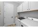 Laundry room with white cabinets, granite countertop, front loading washer, and modern dryer at 5749 Cheech Gln, Bradenton, FL 34211