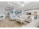 Spacious open-concept living room with wood tile floors, white sofas, and an open flow to the kitchen at 5749 Cheech Gln, Bradenton, FL 34211
