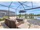 Screened-in patio with lake view, featuring cozy seating and an umbrella-covered table at 5749 Cheech Gln, Bradenton, FL 34211