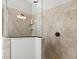 Shower features neutral stone tile walls, glass door, bronze fixtures, and built-in corner shelves at 5749 Cheech Gln, Bradenton, FL 34211