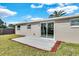 Spacious backyard featuring a concrete patio, a sliding glass door entrance, and ample green space at 6706 Sierra Ter, New Port Richey, FL 34652
