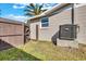 Side view of the backyard featuring a wood fence, air conditioning unit, and lush green lawn at 6706 Sierra Ter, New Port Richey, FL 34652