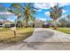 Charming single-story home featuring a spacious driveway, green lawn, and mature palm trees at 6706 Sierra Ter, New Port Richey, FL 34652